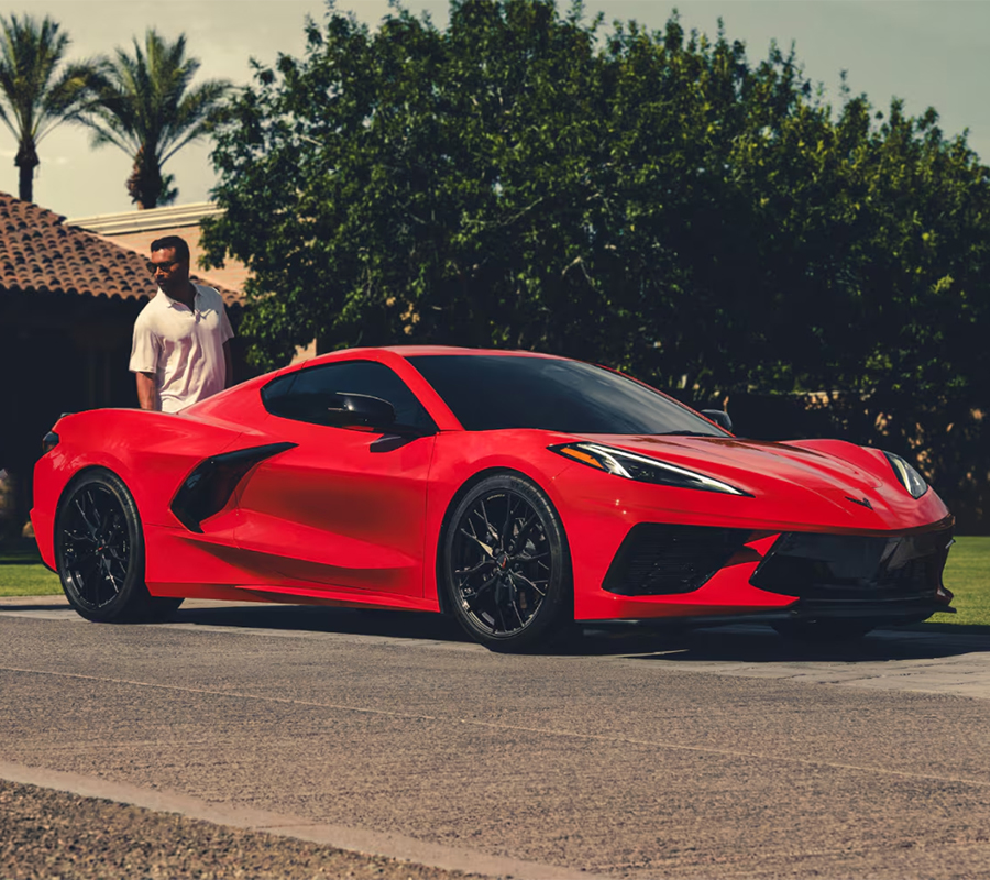 People Standing Next To Red Corvette Stingray