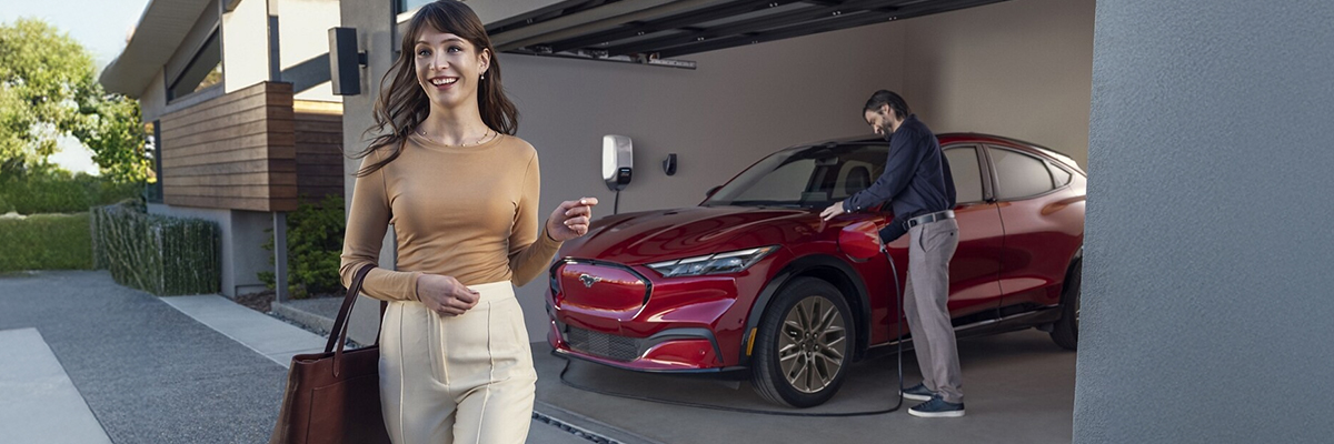 A man and woman standing outside the vehicle in front of a home charger