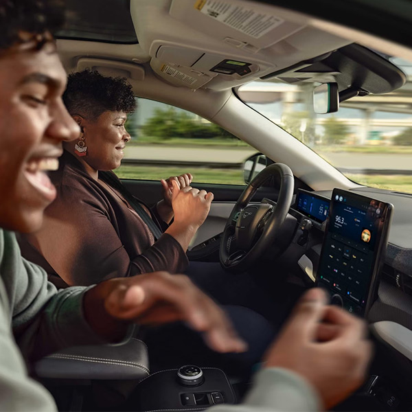 A mother and son smiling in a Mustang Mach-E as they use BlueCruise on the highway.