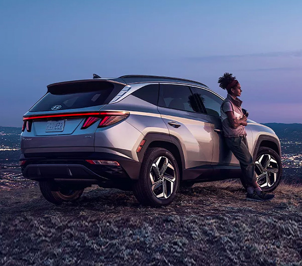 Person leaning on 2022 Hyundai Tucson overlooking city skyline
