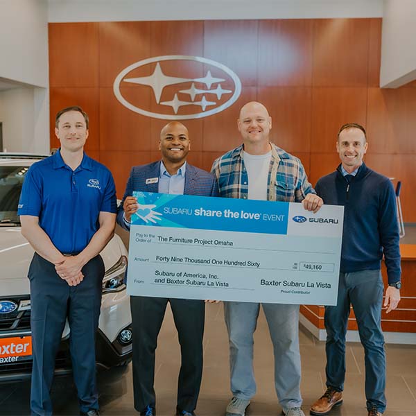 Four men holding a check at a Subaru event.