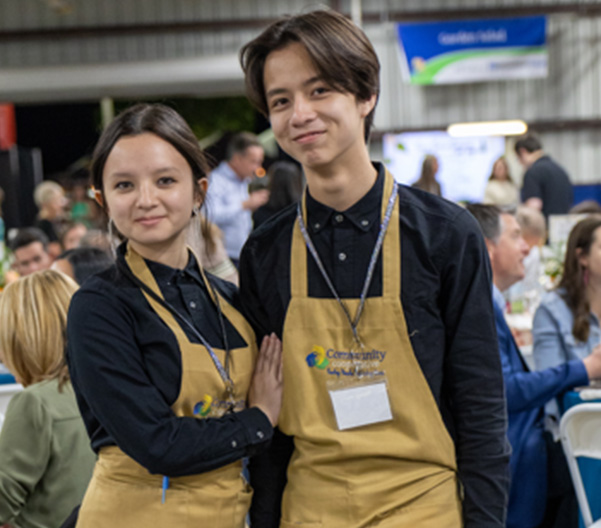 Two volunteers smiling at a community event.