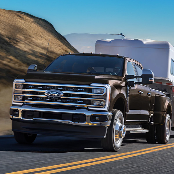 2025 Ford Super Duty® F-350® Lariat® model in Darkened Bronze pulling a camper on a mountain road