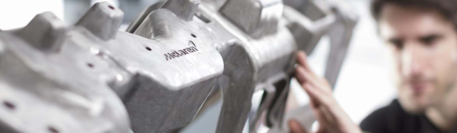 Close up of McLaren service tech inspecting a part