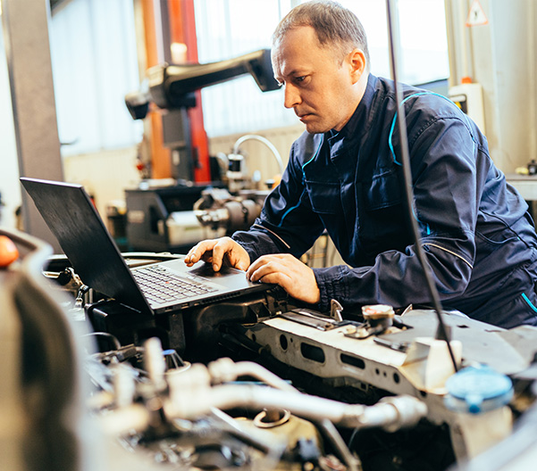 Technician using laptop to diagnose problems in vehicle