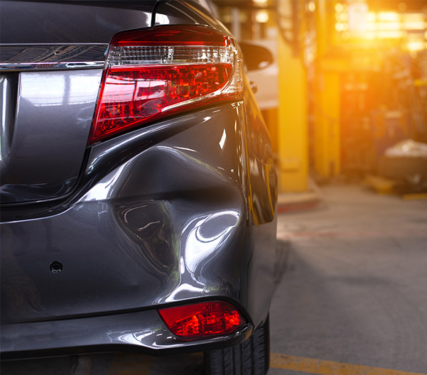 Car with dent on rear dumper in collision center for repair