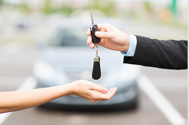 Car salesman handing over keys to a new car