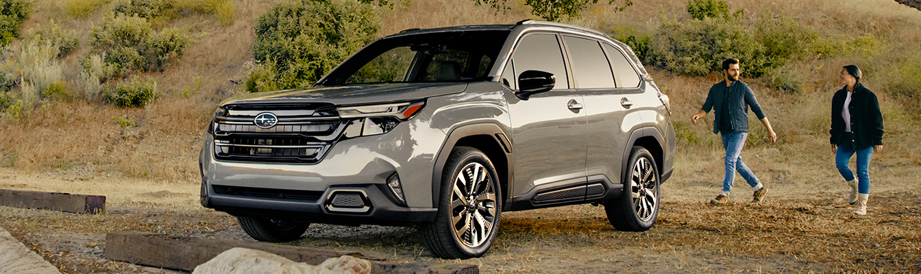 A gray 2025 Subaru Forester Touring parked in the country by a large tree.