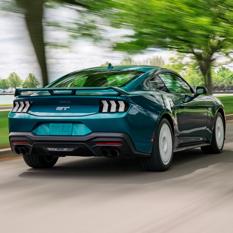 Rear view of a 2026 Ford Mustang® GT Premium fastback with the available FX Package being driven near a lake