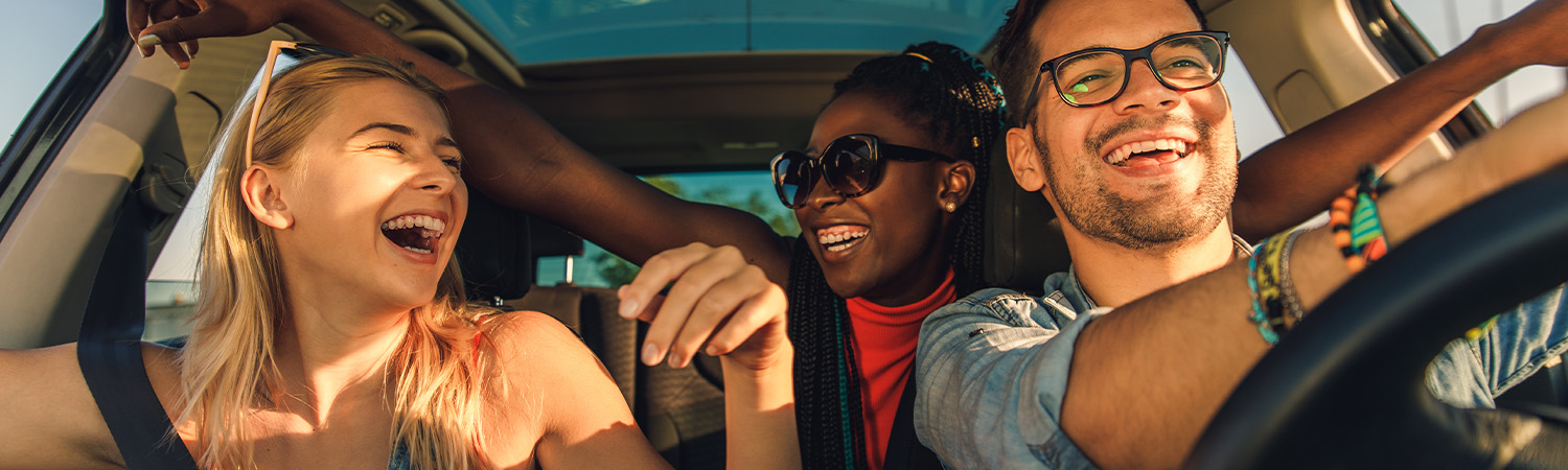 Happy friends driving in car