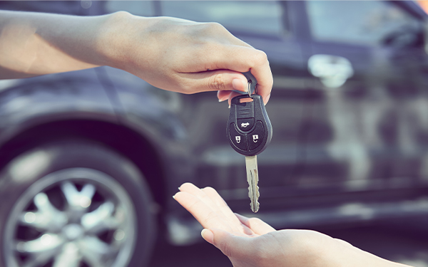 Woman's hand give the car key and blurred background.
