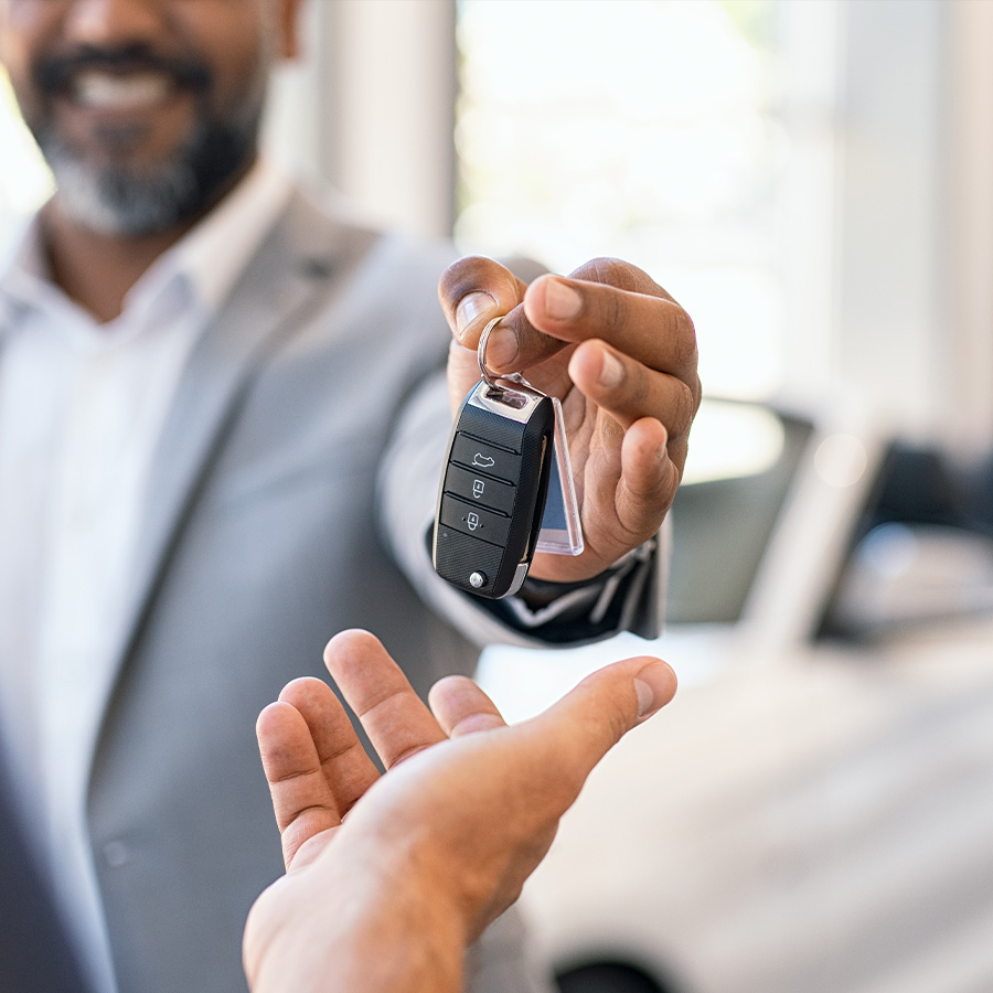 Salesman giving new car keys to customer