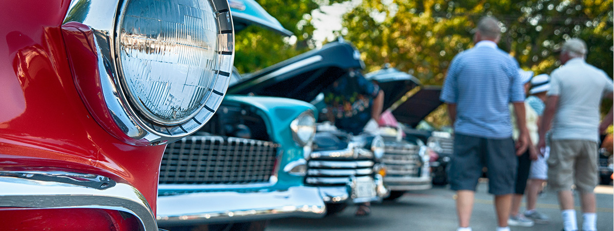 Group of people walking down a vintage car show
