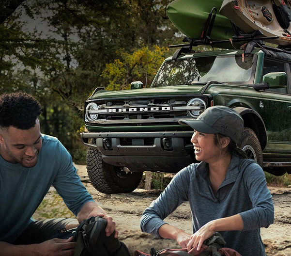 Man and woman sitting infront of Bronco with accesories