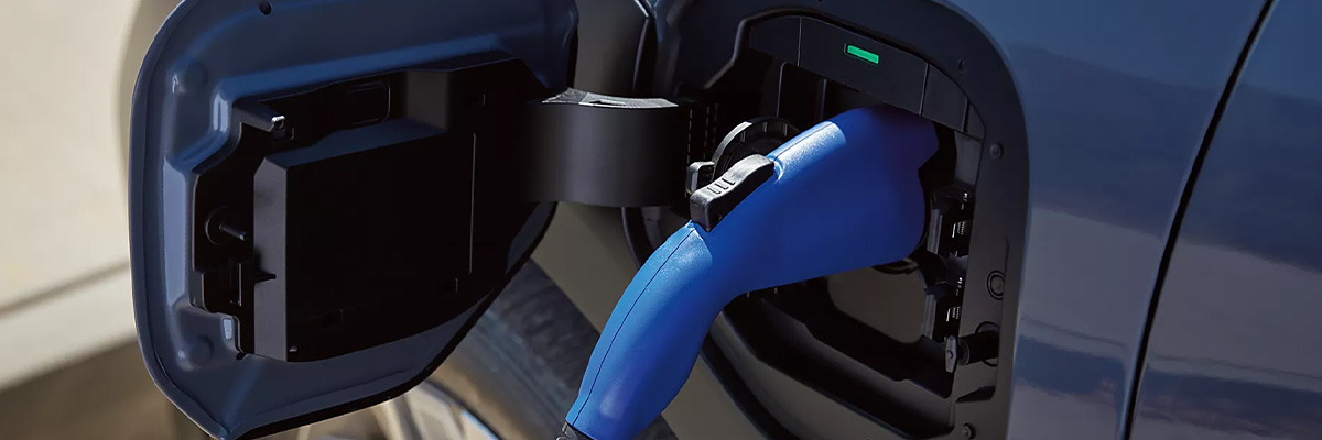 A charging cable plugged into the charging port of a Subaru Solterra EV SUV.