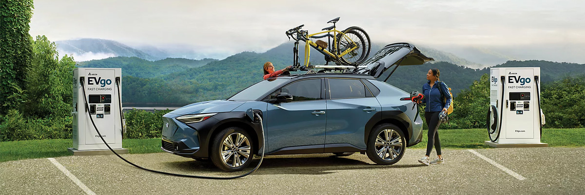 A person charging a Subaru Solterra EV at an EVgo charging station.