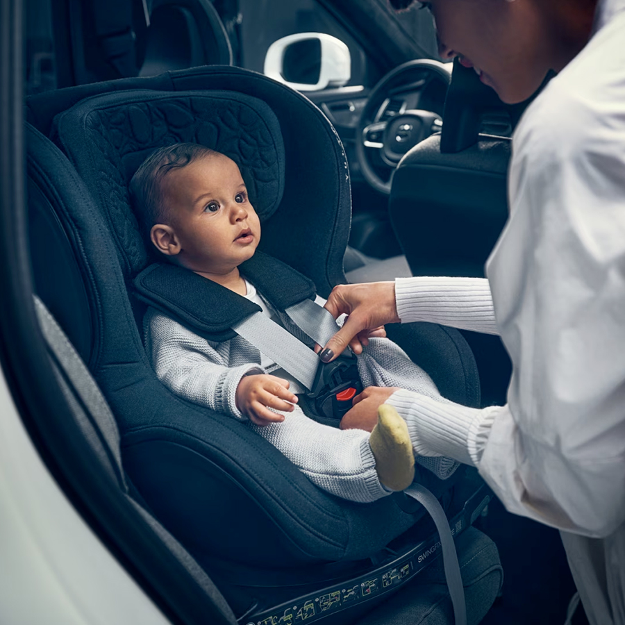 A woman belting a child to the car seat.
