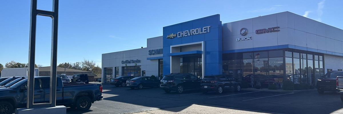 Dealership employee showing customers cars on showroom floor.